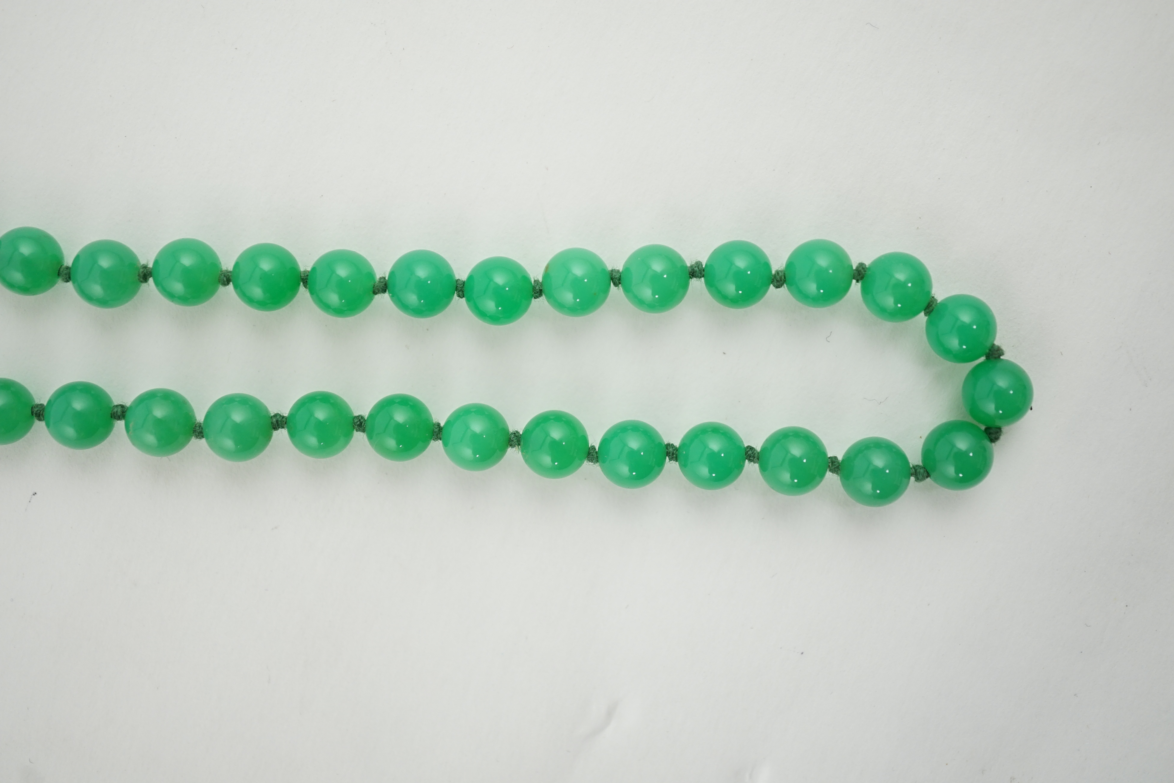 A modern long single strand jadeite bead necklace, with a cabochon jade and diamond chip cluster set 18k clasp